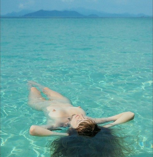 naked girl laying down in the sea